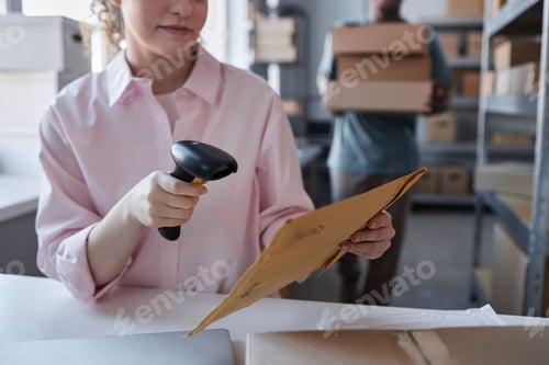 Preview: Close-up of female worker of post office scanning code on envelope