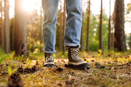 Preview: Feet of an adult wearing boots to travel walking in the forest. Feet walking in outdoor nature