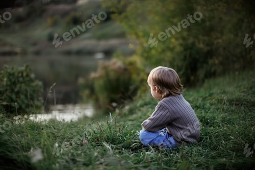 Preview: Sad boy child in sweaters on the shore of the lake, a child look at the water.
