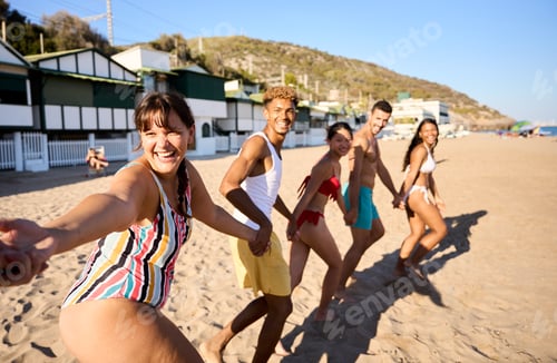 Preview: POV of group diverse young friends holding hands in row in swimwear running excited on sunny beach.