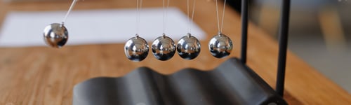 Preview: Newtons Cradle Demonstrating Physics Principles on Wooden Table Indoors