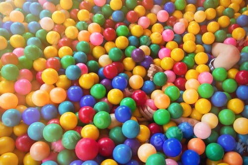 Preview: Portrait of little boy lying on multi colored plastic balls in paddling pool in playing centre