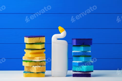 Preview: Stack of new cleaning sponges and liquid detergent against blue wooden background
