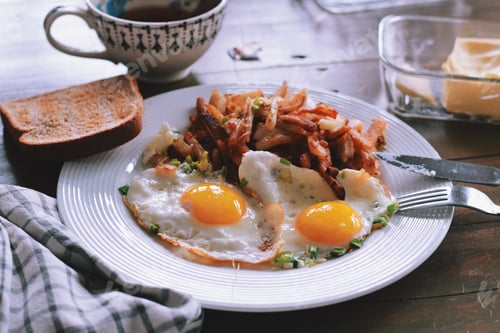 Preview: Two sunny side up eggs and fried potatoes with toast