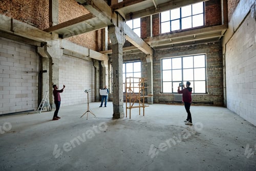 Preview: Two young contractors photographing unfinished structure inside building