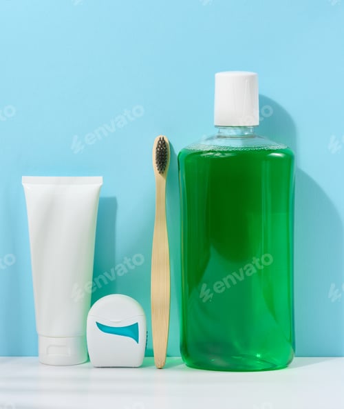 Preview: Refreshing mouthwash in a transparent plastic bottle and dental floss on a blue background
