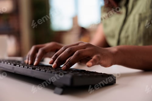 Preview: Closeup of african american influencer writing post for social media on computer keyboard