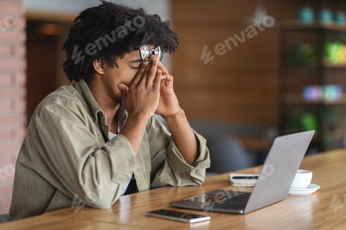 Preview: Tired Black Guy Suffering Eyesight Problem While Working On Laptop In Cafe