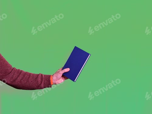 Preview: Man hand holding a blue book on green background, learning concept