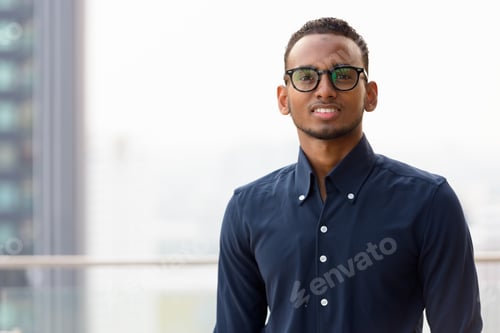 Preview: Portrait of handsome African businessman smiling outdoors at rooftop