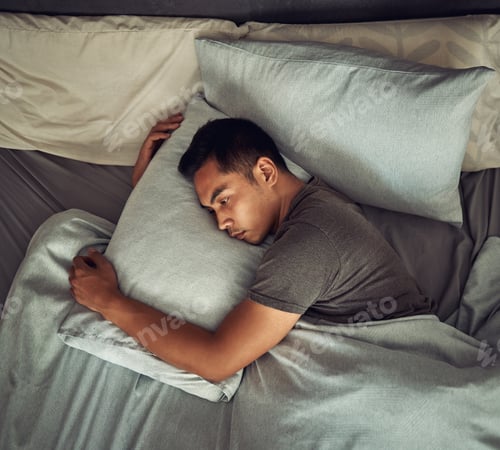 Preview: Shot of a young man lying in bed and looking unhappy at home