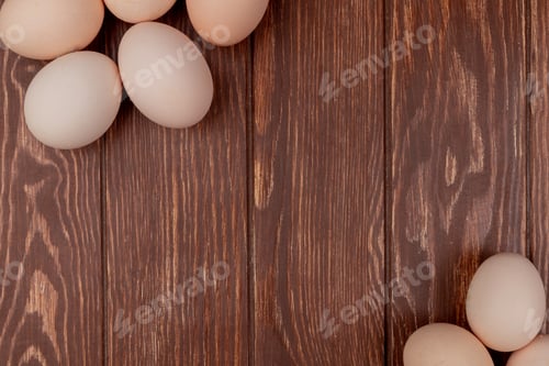 Preview: top view of cream colored chicken eggs isolated on a wooden background with copy space
