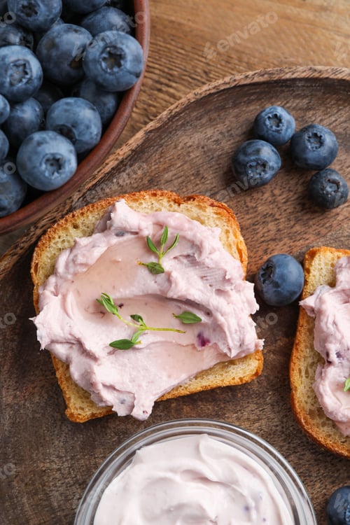 Preview: Tasty sandwiches with cream cheese, thyme and blueberries on wooden tray, flat lay