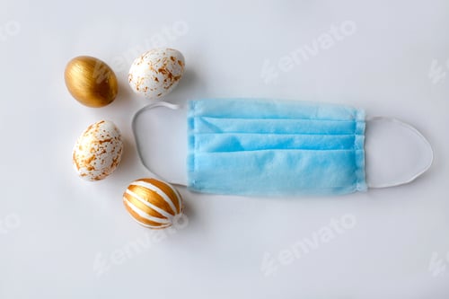Preview: Golden easter eggs and medical mask on a white background. Quara
