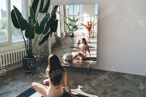 Preview: Slim woman taking photo in mirror reflection during training