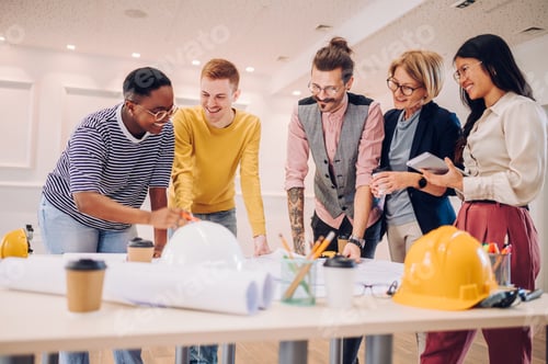 Preview: Multiracial team of architects having a meeting while using blueprints