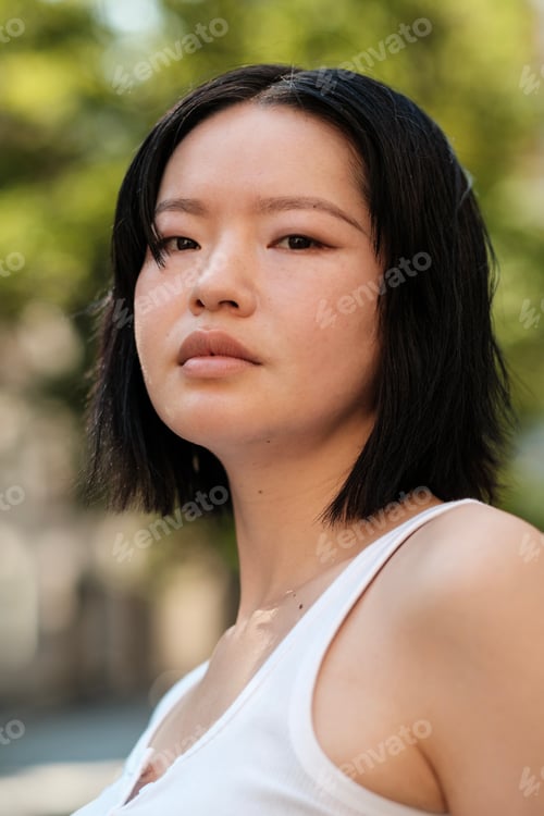 Preview: Young asian woman posing with serious expression outdoors