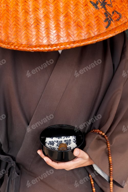 Preview: Close up of Japanese monk wearing traditional clothing holding alms bowl.