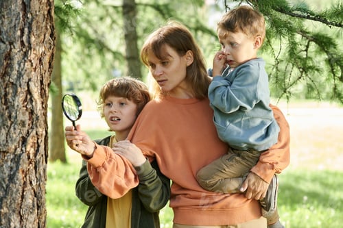 Preview: Mother with Two Boys Holding Magnifying Glass Exploring Nature in Forest