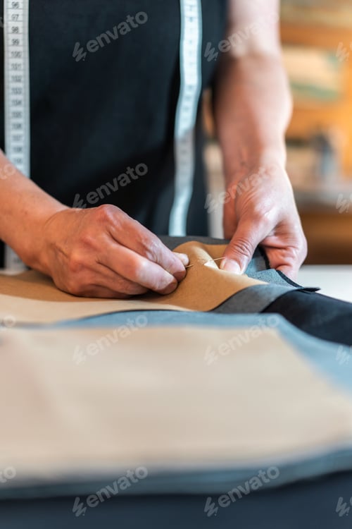 Preview: Fashion designer putting pins into pattern and fabric. Vertical shot