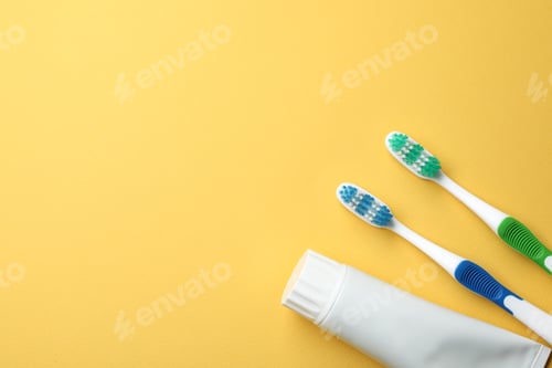 Preview: Blank tube of toothpaste and brushes on color background, top view with space for text
