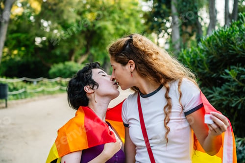 Preview: Lesbian couple kissing and showing lgbt flag at pride parade