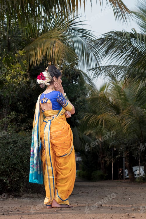 Preview: Vertical shot of a woman in a traditional sari at a tropical park