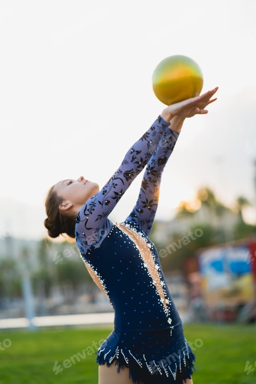 Preview: Young flexible rhythmic gymnast practicing with a golden ball.