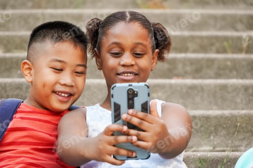 Preview: Close up of happy multiethnic children using mobile phone for vlogging
