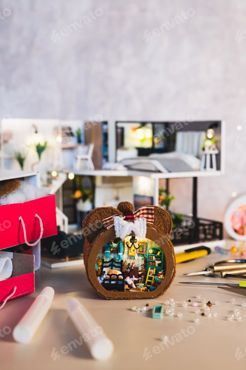 Preview: Glue and beads for decorating a tiny miniature house on a table vertical view