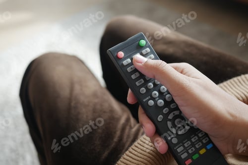 Preview: close up of women hand holding tv remote.