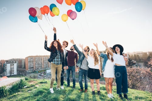 Preview: Portrait of group of friends, standing on roof, holding helium balloons