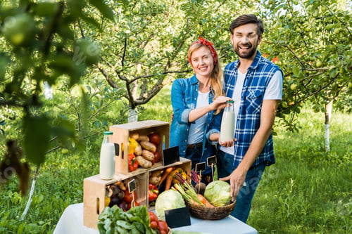 Preview: couple of farmers showing bottle of milk at farmer market