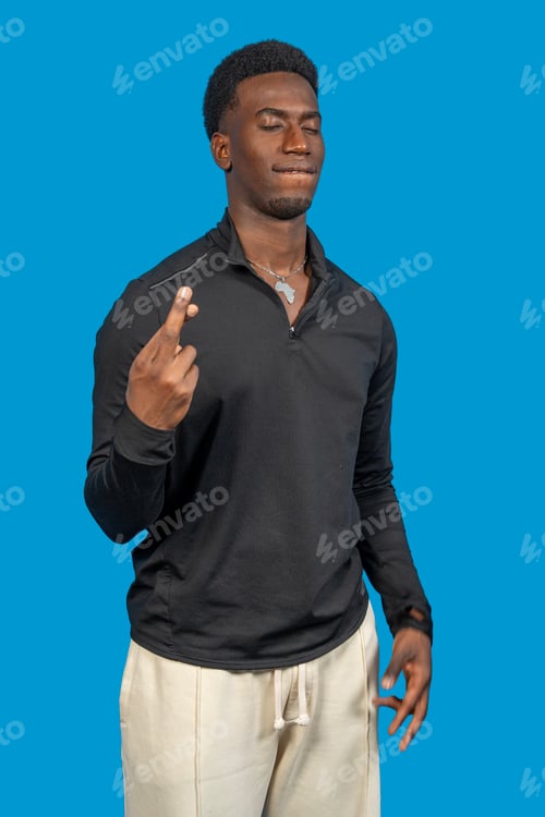 Preview: Young man crossing fingers making a wish on blue background
