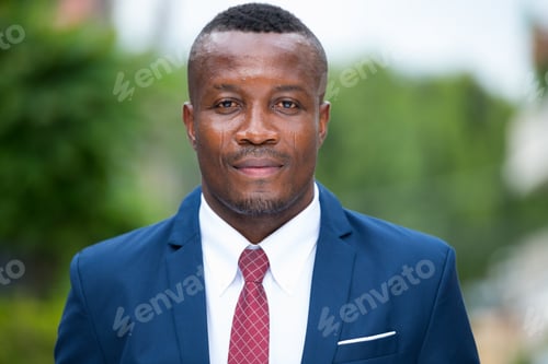 Preview: Young African businessman wearing blue suit outdoors