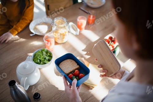 Preview: Close-up of mother preparing snack to lunch box in kitchen at home