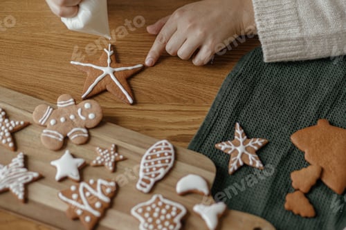 Preview: Decorating gingerbread cookies with icing on rustic wooden table top view