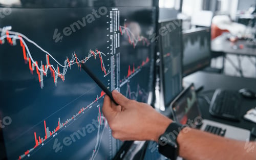 Preview: Close up view of man's hand that points at part of stock graph on display