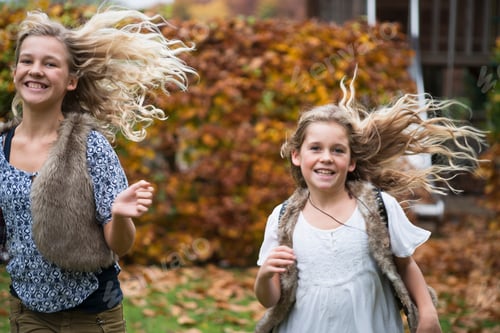 Preview: Two sisters with long blond hair running in autumn garden