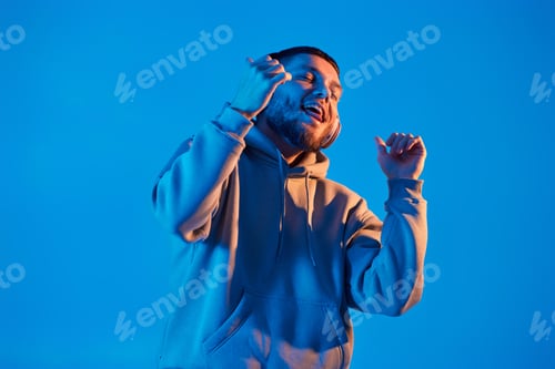 Preview: man with headphones in sweatshirt enjoying favorite music