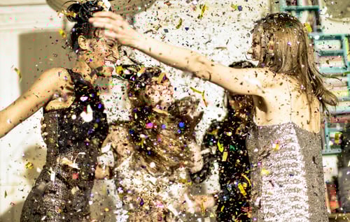 Preview: Group of young women celebrating at a party in a haze of falling glitter confetti.