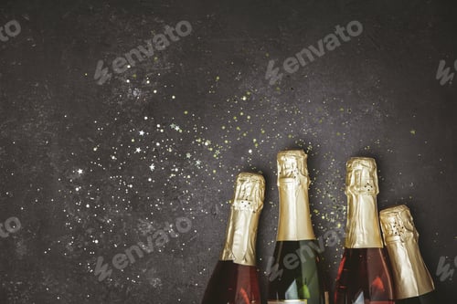 Preview: Bottles of champagne with gold glitter and space for text on dark background
