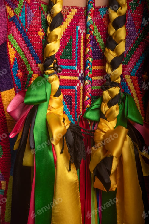 Preview: A person wearing a colorful dress with two long braided ribbons