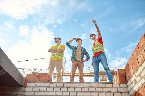 Preview: Men standing on brick wall of building under construction