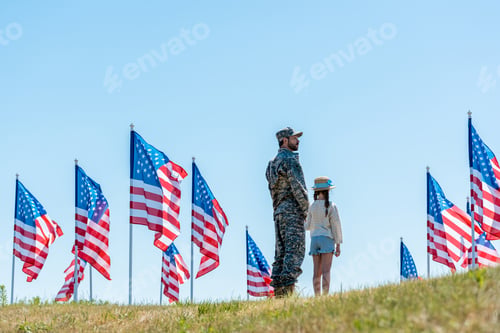 Preview: military man in uniform standing with daughter near american flags