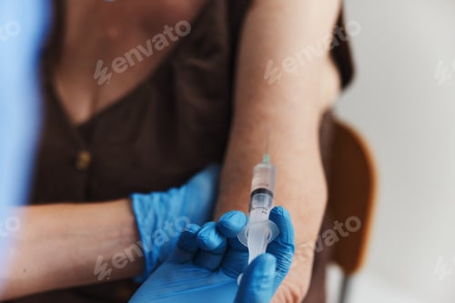 Preview: doctor makes an injection in the arm of a patient covid passport close-up