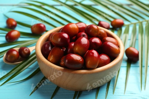 Preview: Palm oil fruits in bowl on turquoise wooden table, closeup