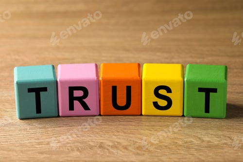 Preview: Colorful cubes with word TRUST on wooden table