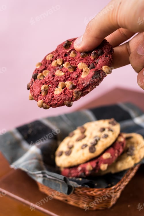 Preview: Hand Holding Chocolate Chip Cookie on Pink Background