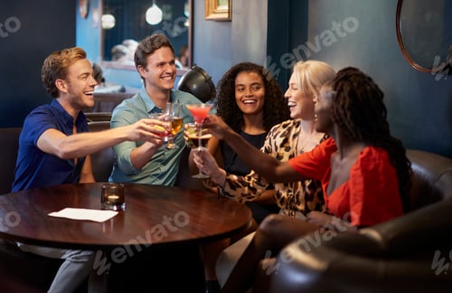 Preview: Group Of Young Friends Sitting Around Table And Making A Toast In Bar On Night Out